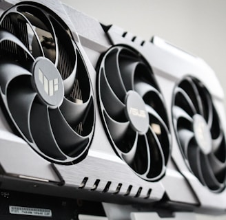 A close-up view of a graphics card with three large cooling fans and metallic accents. The card is housed within a computer case, showcasing intricate hardware design.