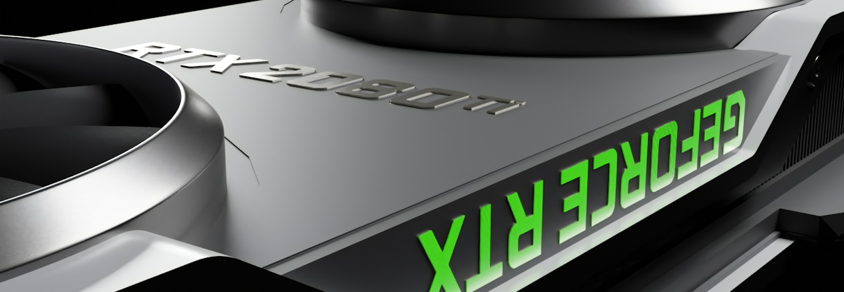 Close-up of a graphics card featuring two large cooling fans and the text 'GEFORCE RTX' displayed in green. The metallic surface has a sleek, modern design with embossed characters 'RTX 2080 Ti'.