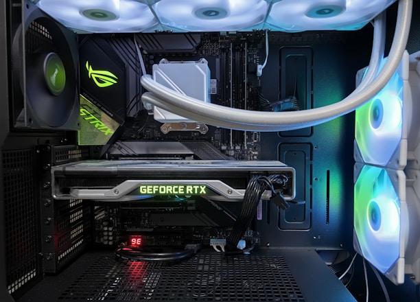 A high-end gaming or performance PC interior equipped with RGB lighting and multiple cooling fans. The graphics card prominently displayed is a GeForce RTX model, with branding visible. The setup includes neatly managed cables and a liquid cooling system.